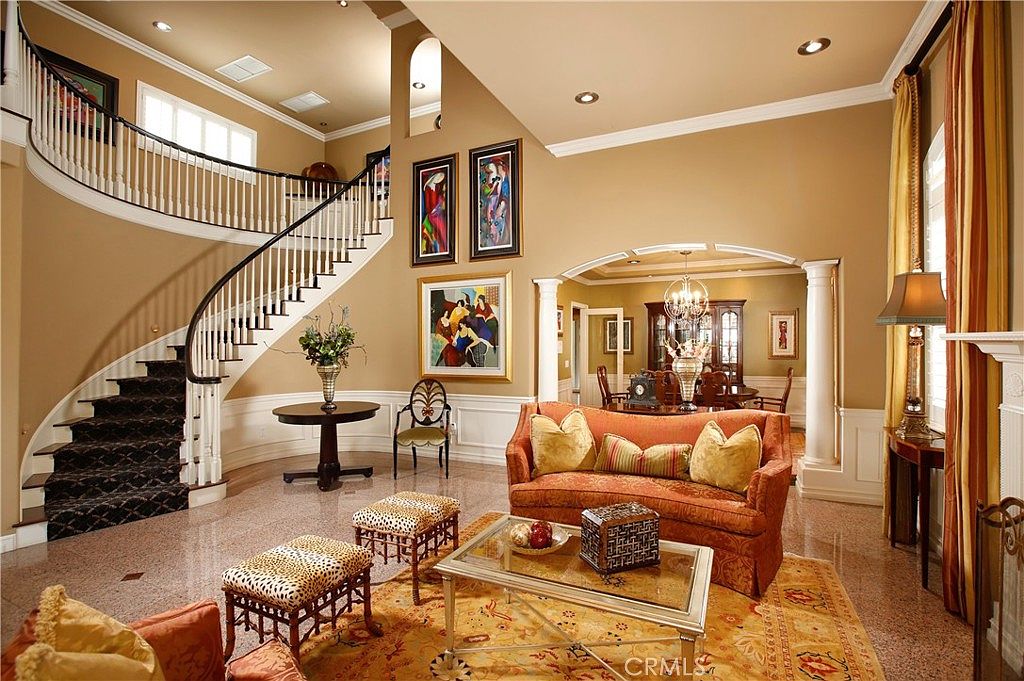 The grand foyer with a curved staircase, granite floor, and double-height ceilings