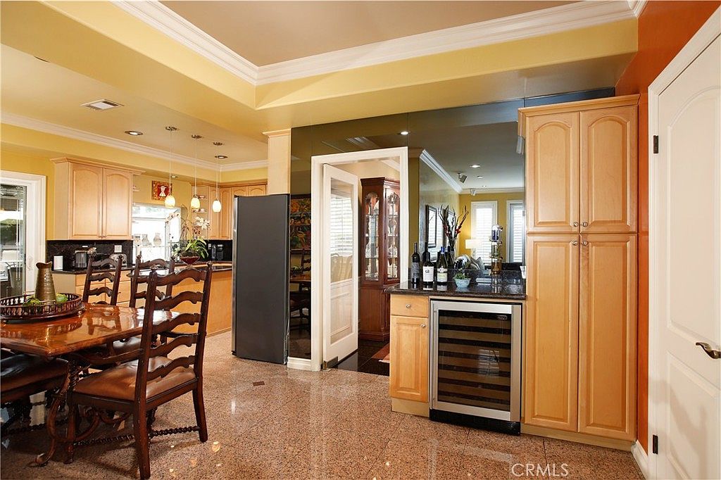 A kitchen with maple cabinetry, a built-in wine cooler, and granite counters opening to the dining area